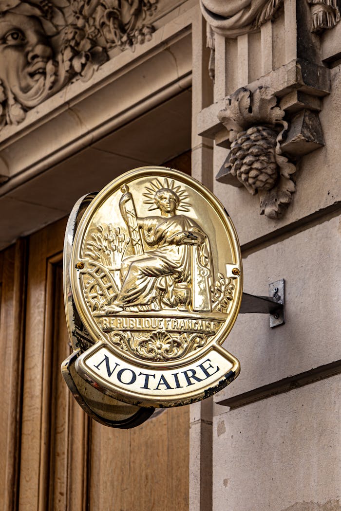 services-03 Classic notary sign on a historic Parisian building facade in daylight.